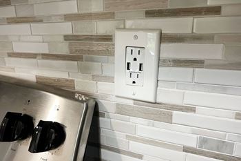 An electrical outlet on a brick wall in a kitchen